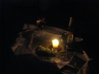 Romantiškai paruoštas staliukas prie žvakių šampano ir vynuogių